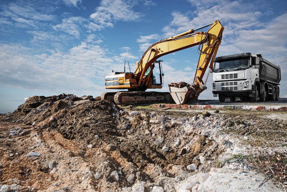 Excavator and truck on a construction site Excavator and truck digging resources on new construction site