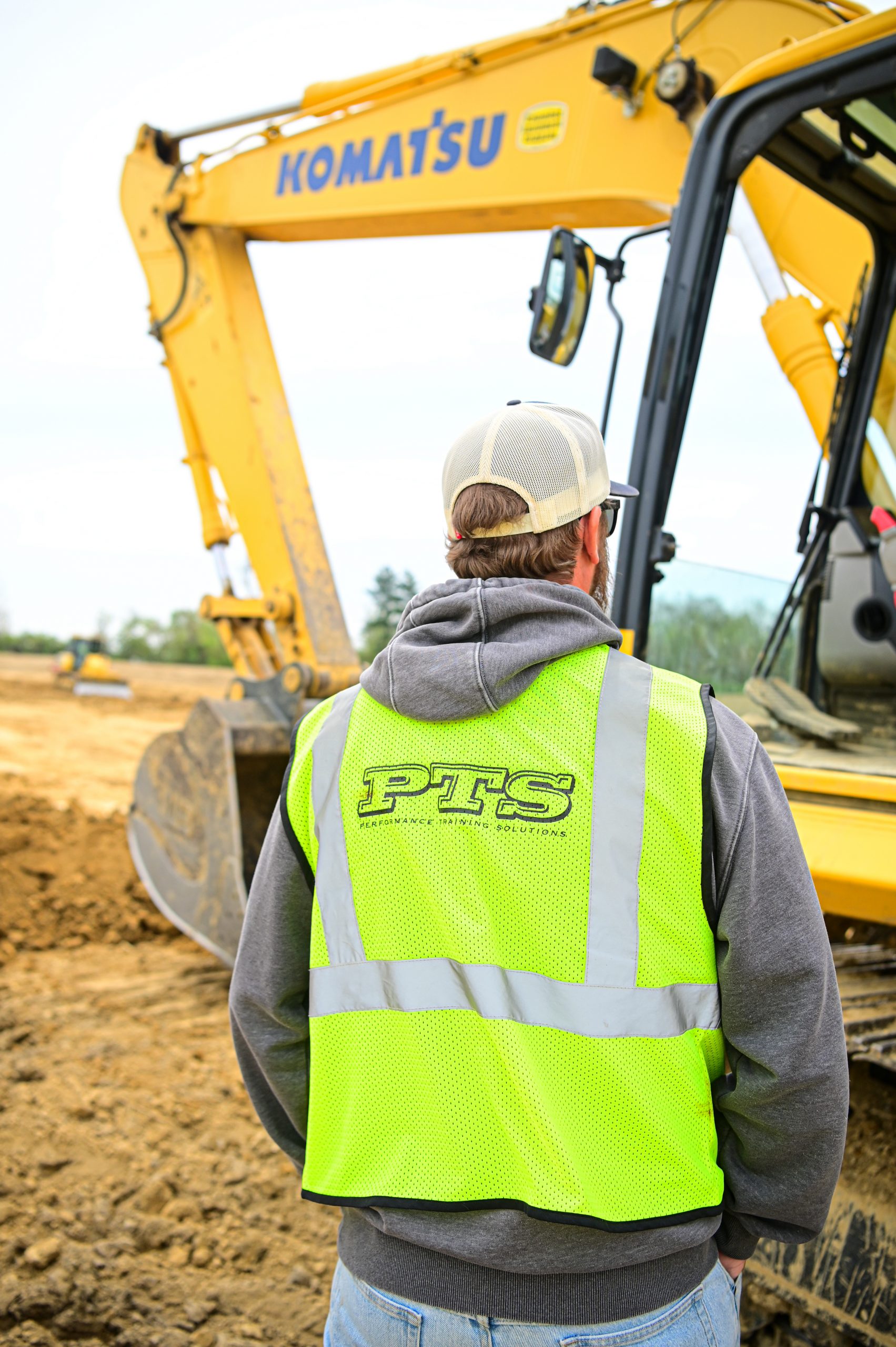 An image of a man standing in front of heavy equipment, demonstrating how veterans in construction can find success.